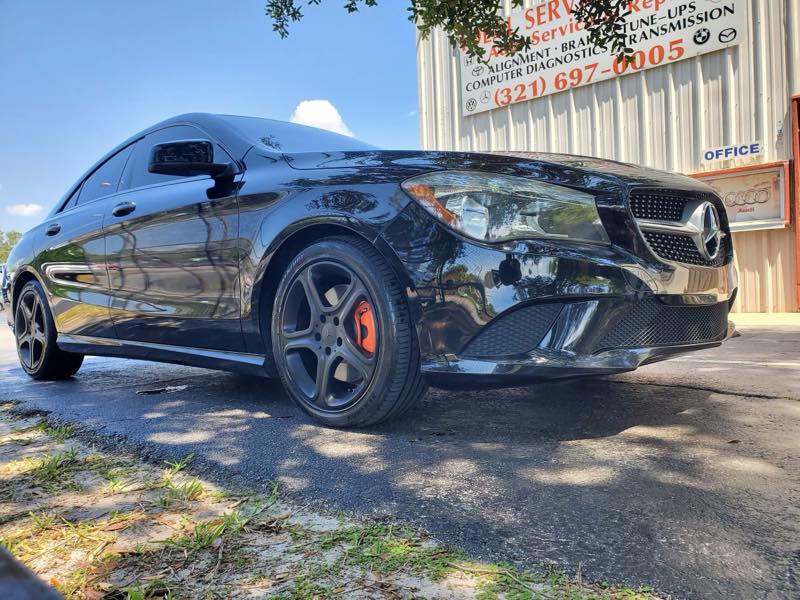 Customer Mercedes CLA parked outside Ideal Service Center, shop signage behind
